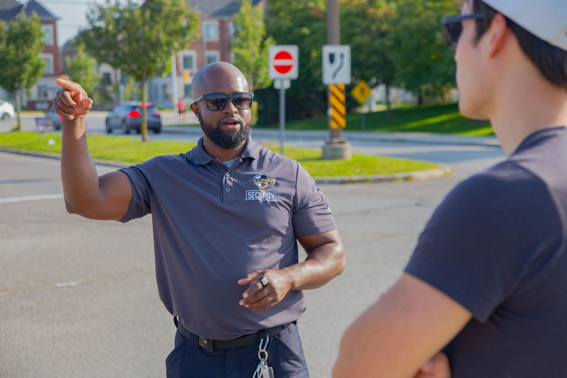 A male Flex Point Security guard interacting with an employee next to a set of stairs in a corporate office