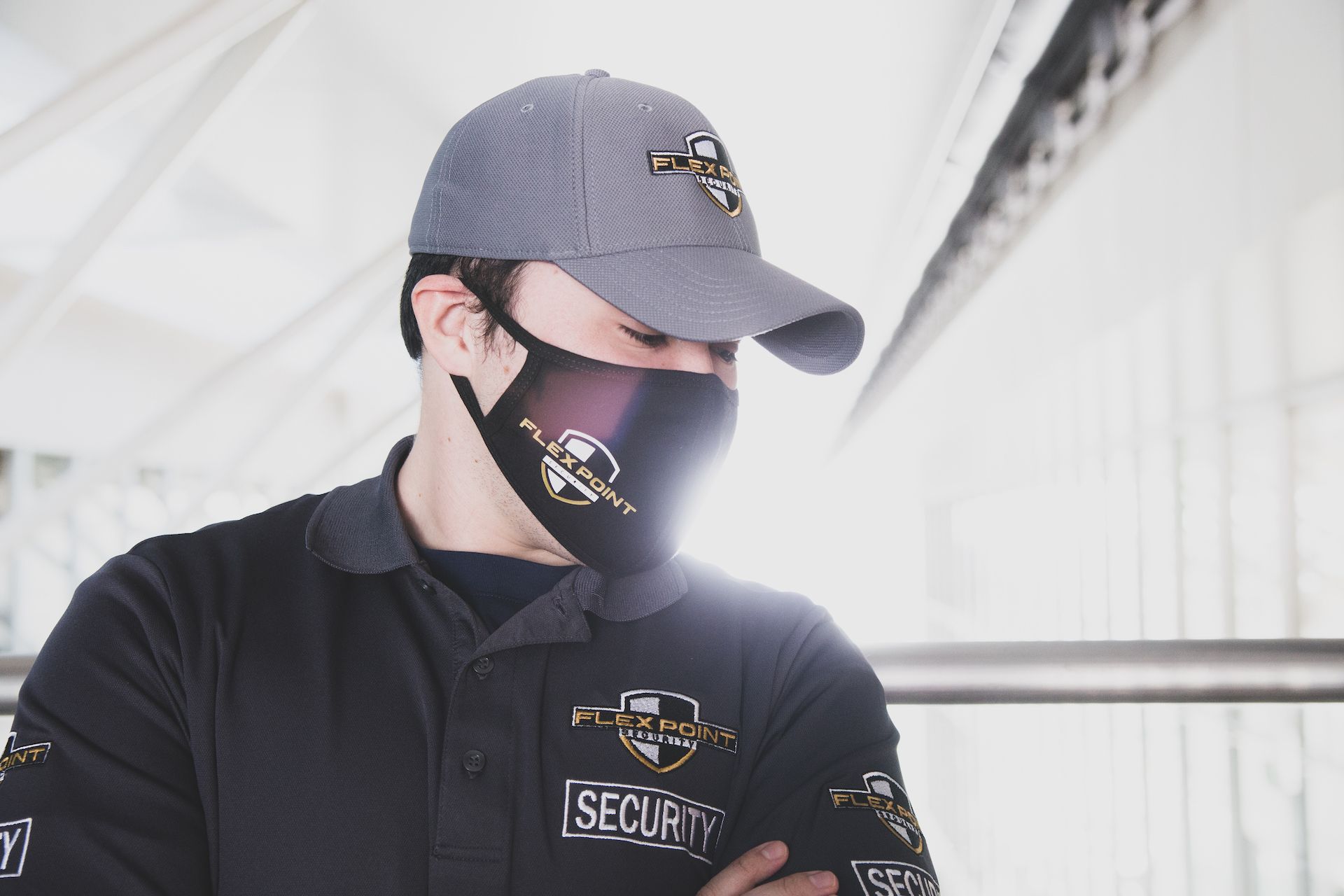 Close up of a male Flex Point Security guard wearing a branded Flex Point Security t-shirt, hat and face mask
