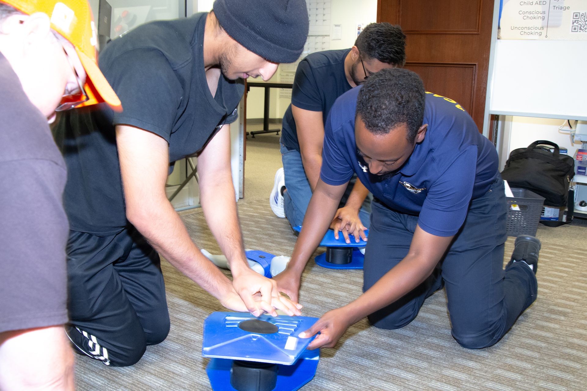 A Flex Point Academy instructor on the ground teaching a trainee with a blue dummy / mannequin