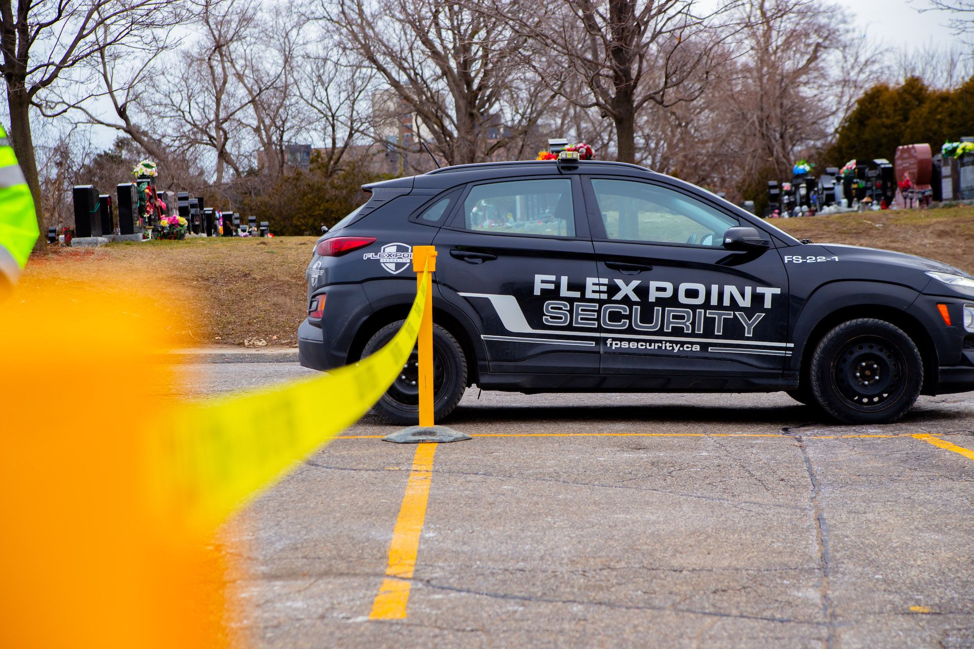 A Flex Point Security mobile patrol vehicle parked in a parking lot next to two pylons that have yellow caution tape between them