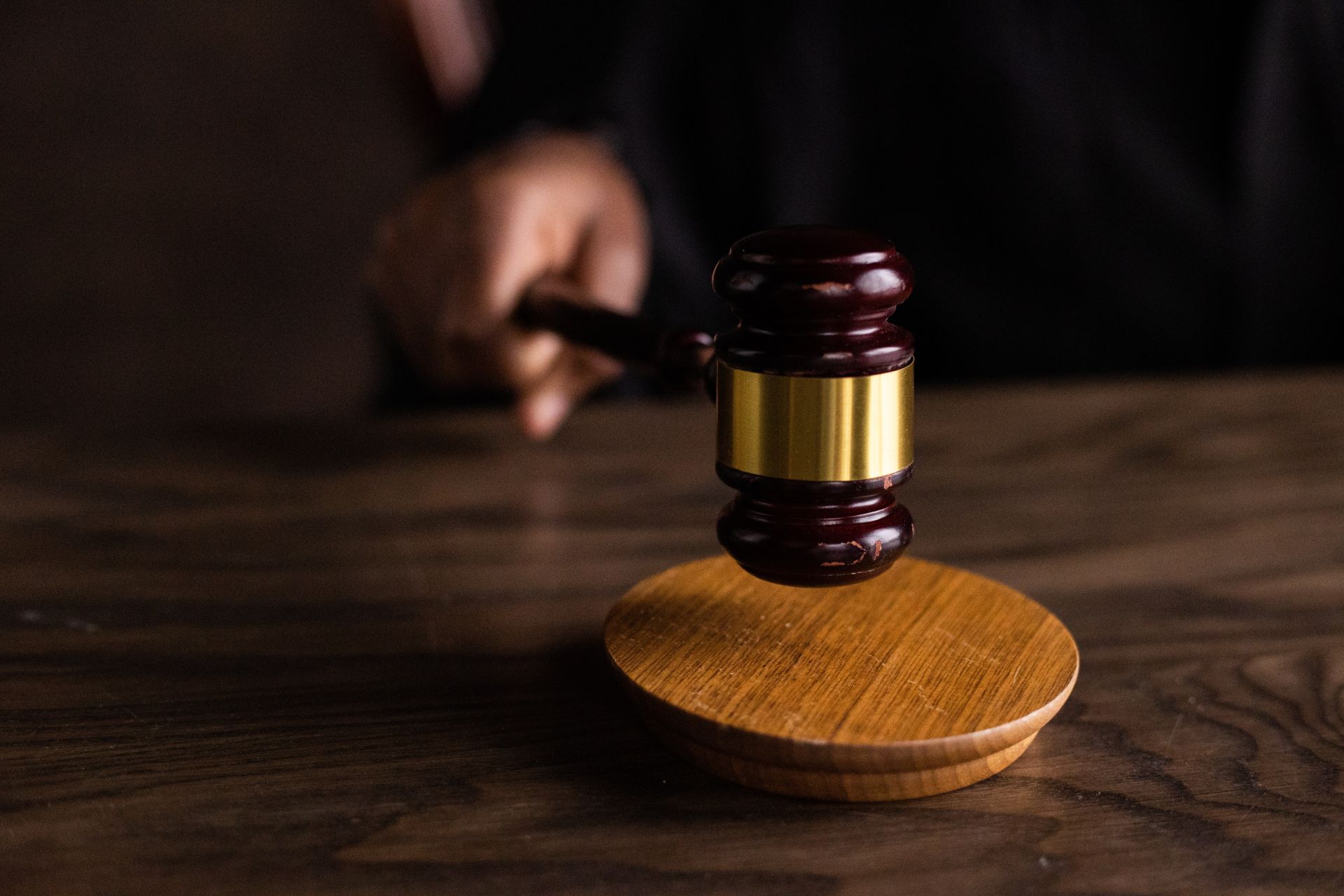 Close up of a handing holding a gavel that is close to being hit against a sound block