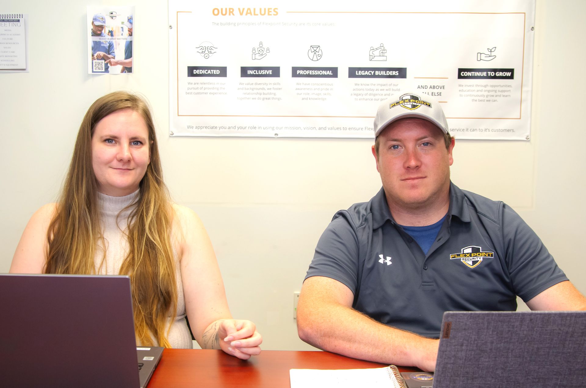 A male and female Flex Point Security employees sitting with their laptops open as they completes interviews for security guard role openings