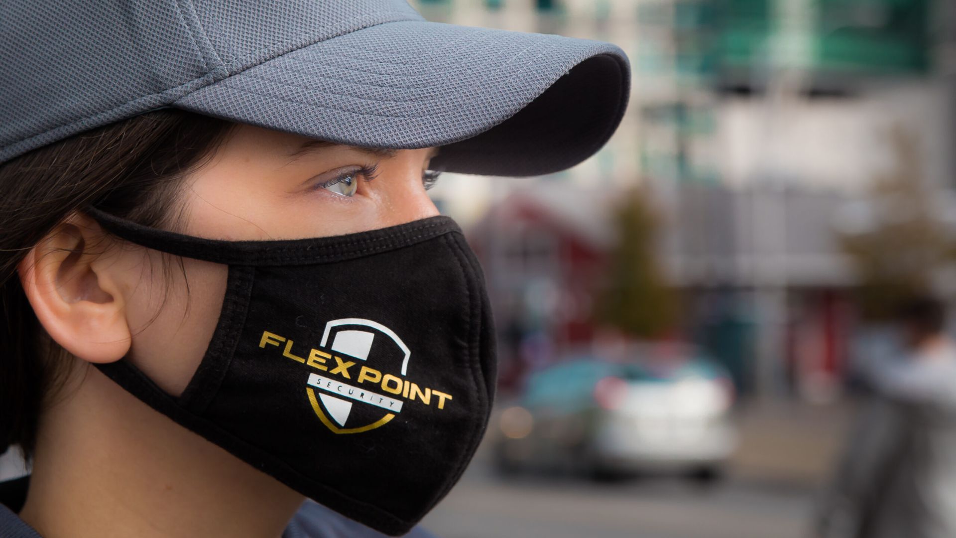 Close up of a female Flex Point Security guard's head as she wears a branded grey hat and black face mask