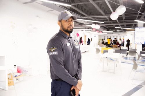 A male Flex Point Security guard standing with his arms folded at an event where he is providing security services