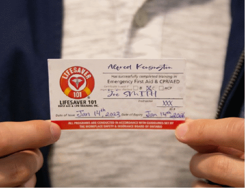 Close up of an individuals fingers holding a card from Lifesaver 101 showing they have successfully completed Emergency First Aid & CPR/AED training