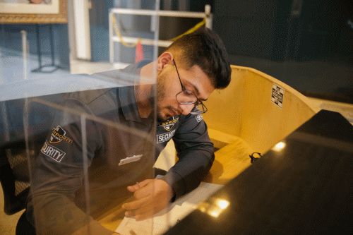 A male Flex Point Security guard seated at a desk in a client's building writing a security report