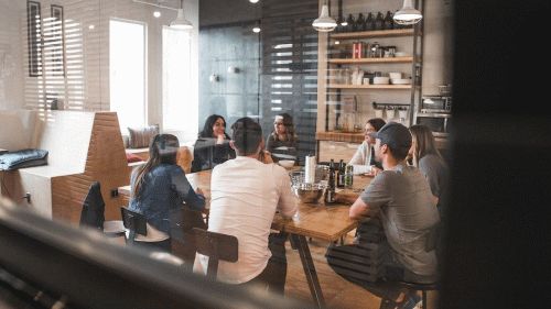 A group of people sitting at a table in an office having a conversation