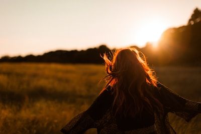 Woman walking in field toward sunburst