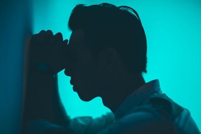 Silhouette of man leaning against the wall looking tired and upset
