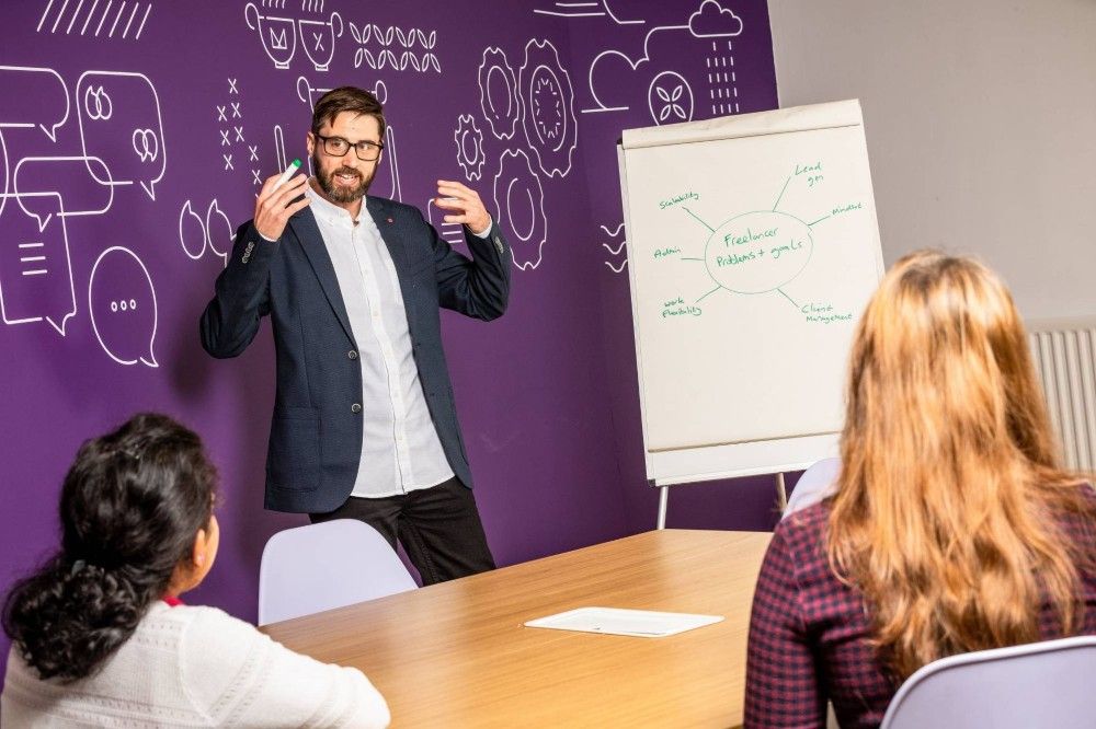 Presenting to a group with flip chart paper in front of a purple background