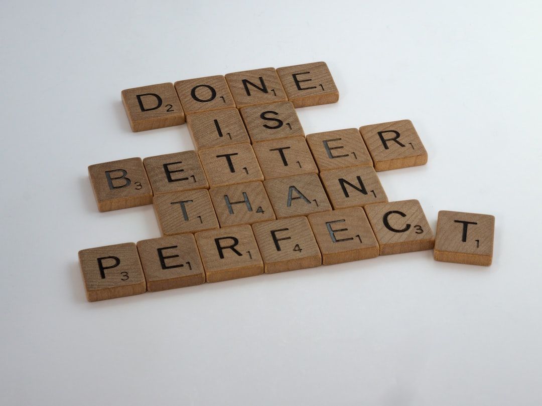 Some wooden dominos spelling the words done is better than perfect