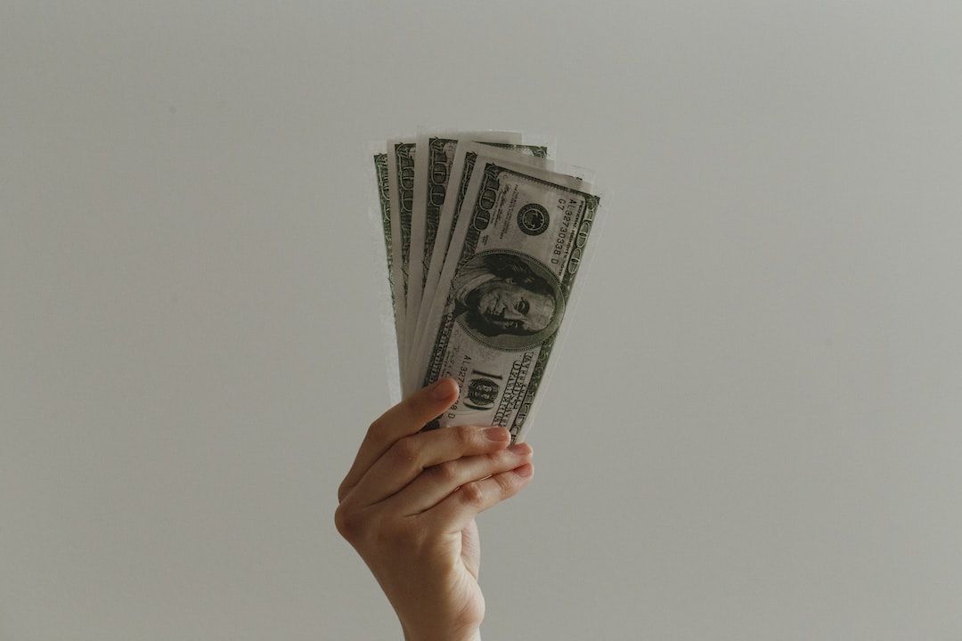A hand holding some 100 dollar bills