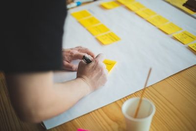 Hands writing on yellow sticky notes