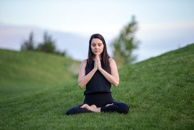 Woman meditating on green hill