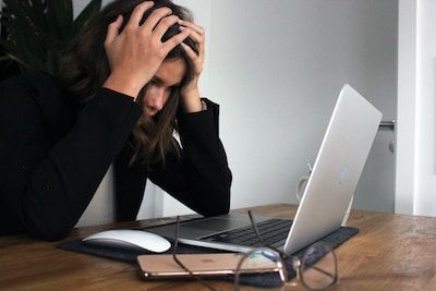 Woman holding head in hands at laptop