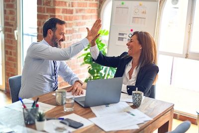 Man and woman high-fiving at laptop