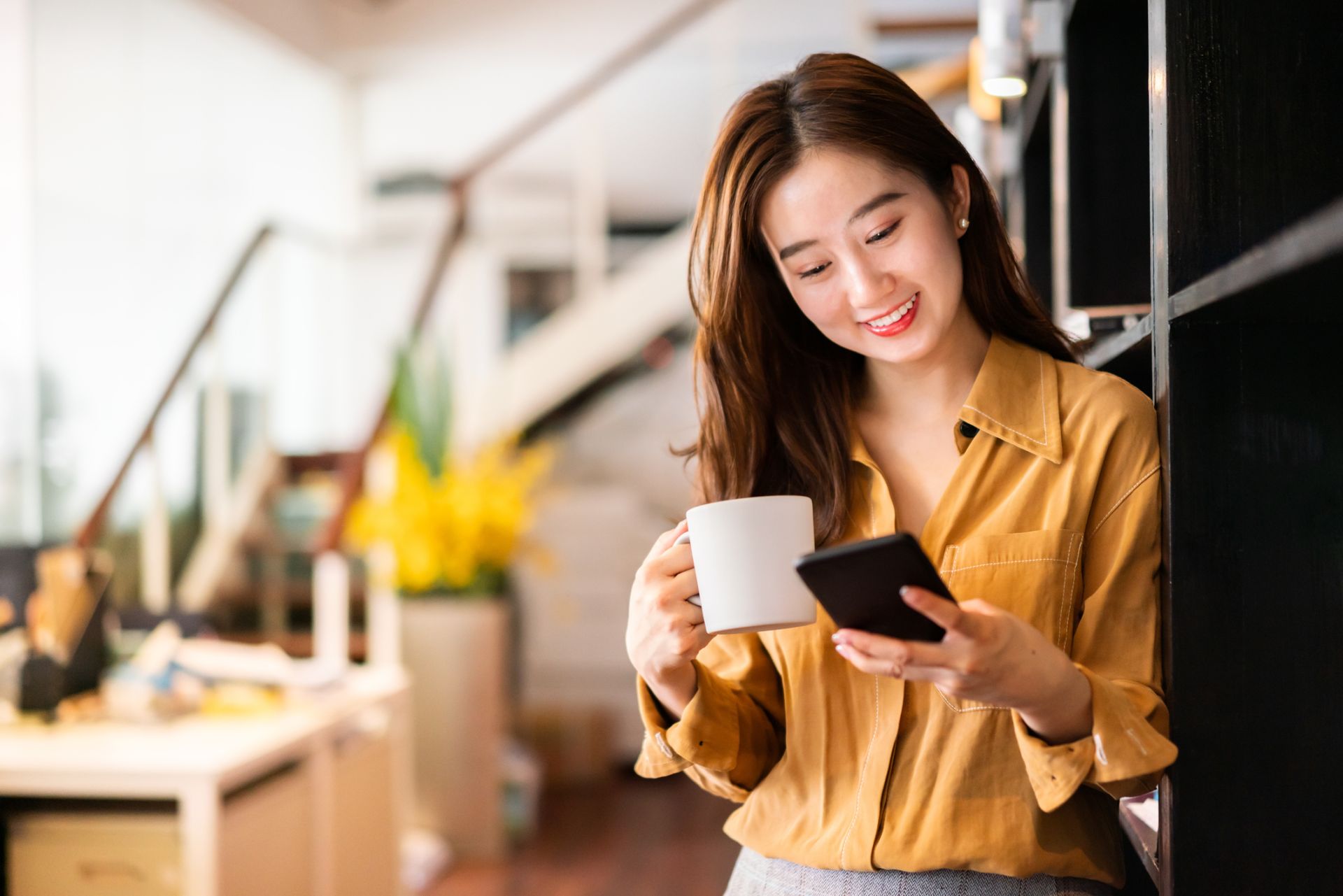 Lady with cup reading a device