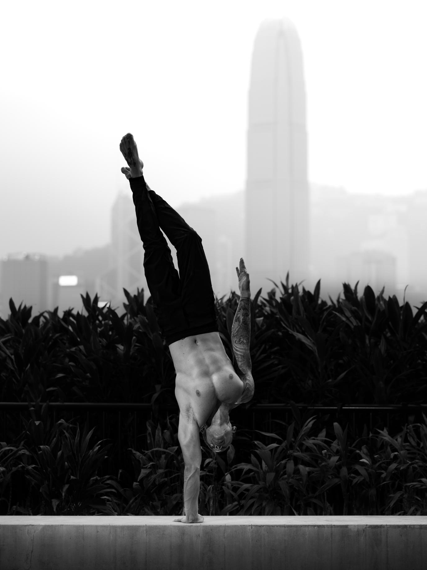 Miguel in a handstand on a ledge above Hong Kong harbour