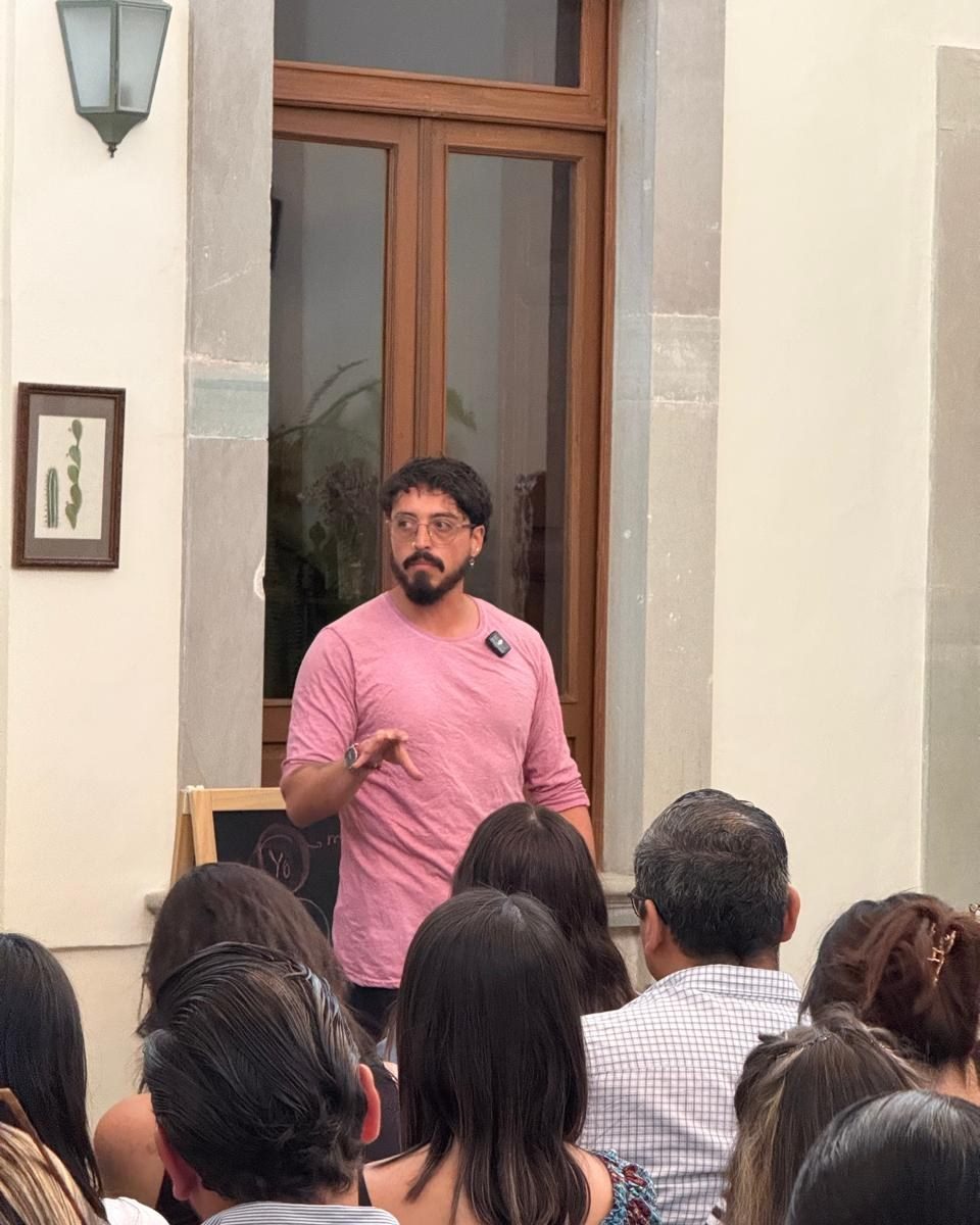 Andrés habla ante un grupo; en primer plano, personas de espaldas.