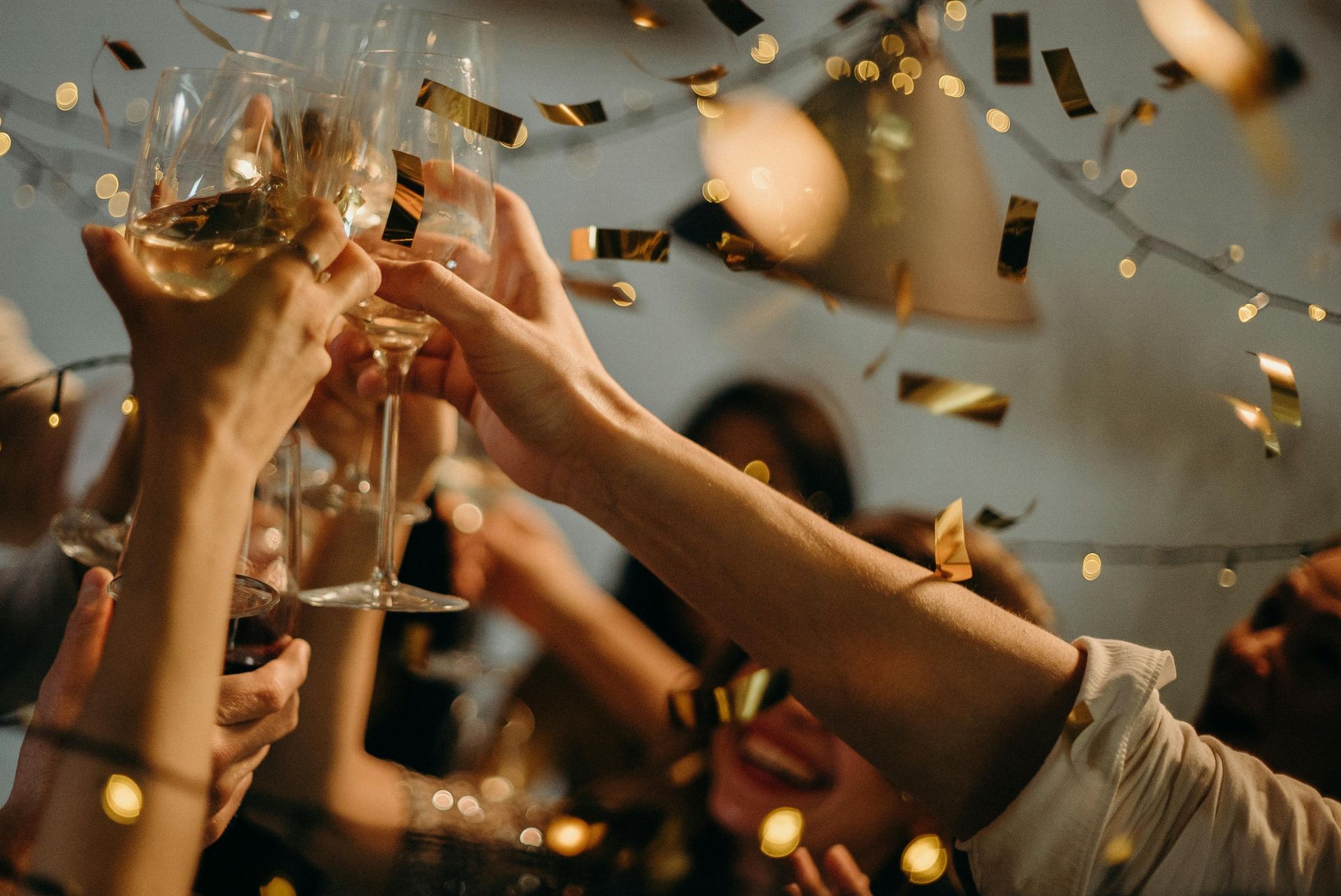 A group of colleagues are toasting with glasses amongst gold confetti