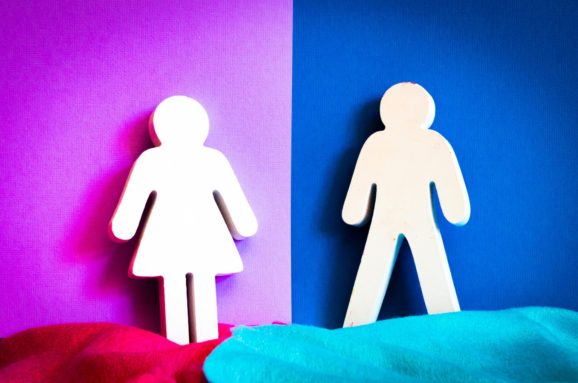 A female and male symbol side by side, with a split pink and blue background down the middle
