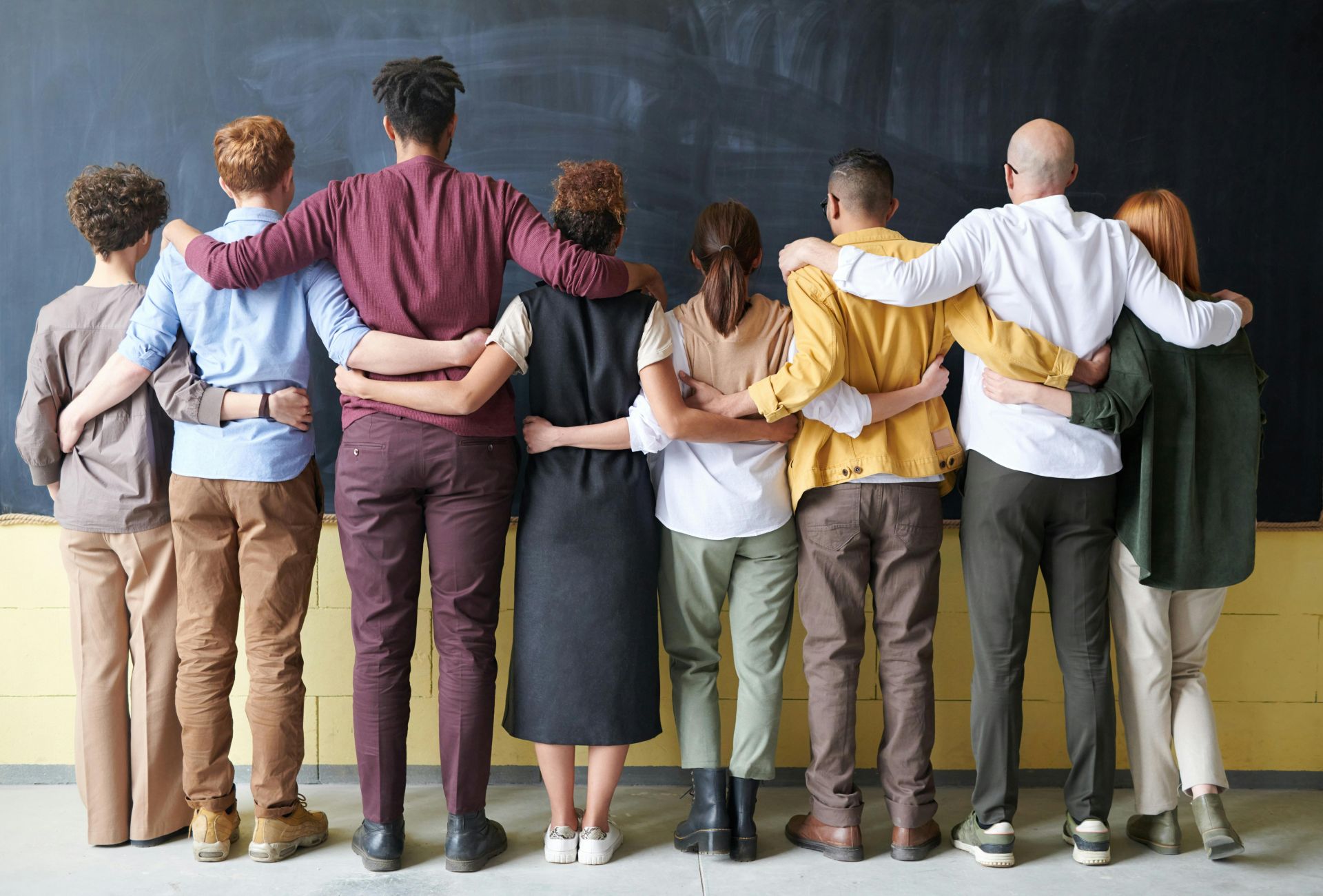 A group of colleagues with their backs to the camera link arms