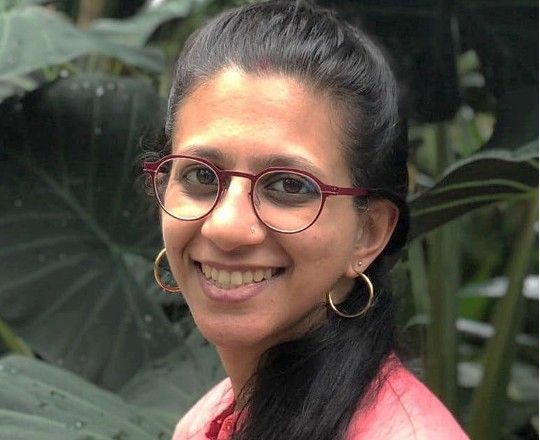 Uma Sharma smiling, photographed among tropical plants