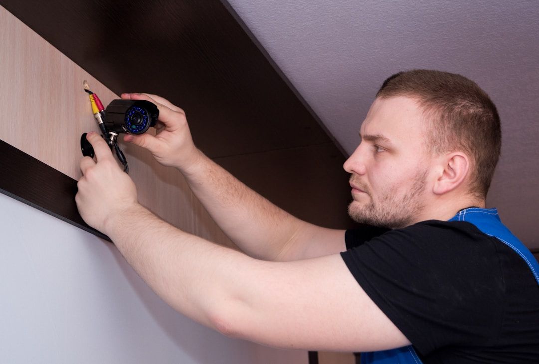 A man installing a security camera on a wall or ceiling