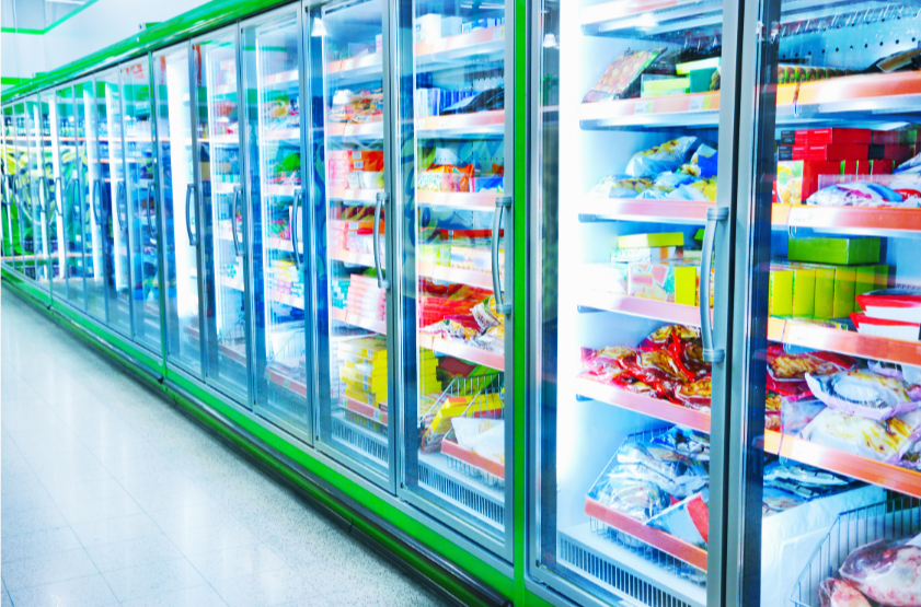 Commercial refrigeration aisle with modern glass-door freezers displaying frozen foods, energy-efficient LED lighting in green and blue, supermarket cold storage equipment