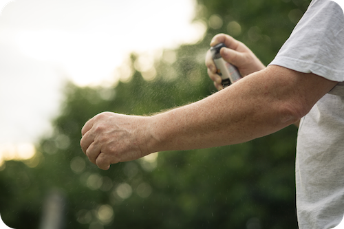 Mann sprüht Arm mit Insektenschutzspray ein