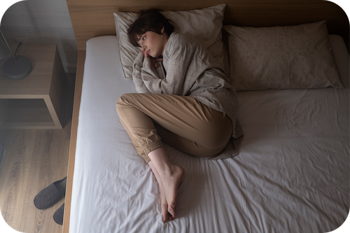 Frau liegt bedrückt im Bett