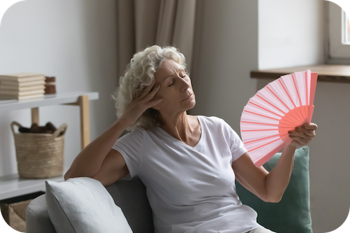 Frau sitzt auf dem Sofa und fächert sich Luft zu
