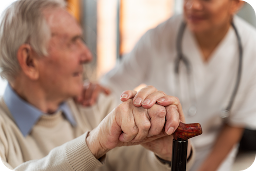 Senior mit Gehstock schaut Pflegekraft an