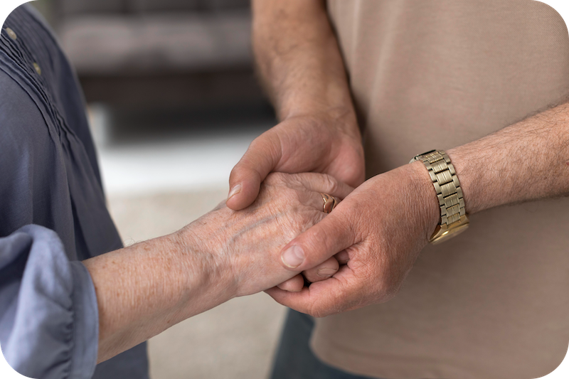 Sohn hält die Hand seiner pflegebedürftigen Mutter