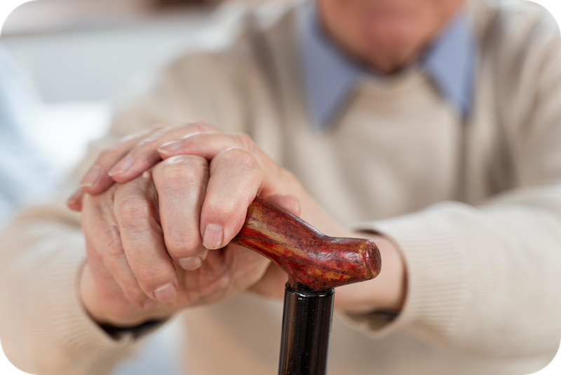 Pflegebedürftige Person hält Stock