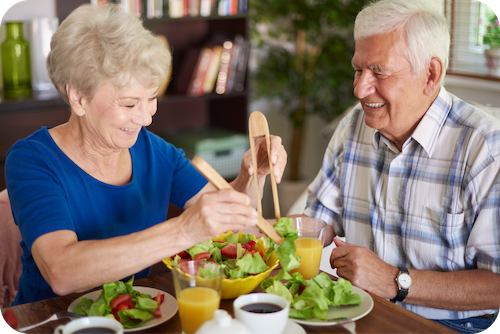 Zwei Senioren sitzen am Tisch und essen Salat