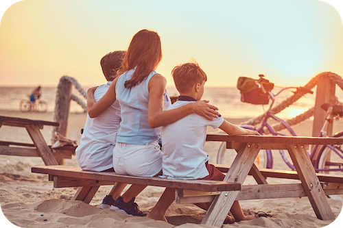 Familie sitzt auf einer Bank am Strand