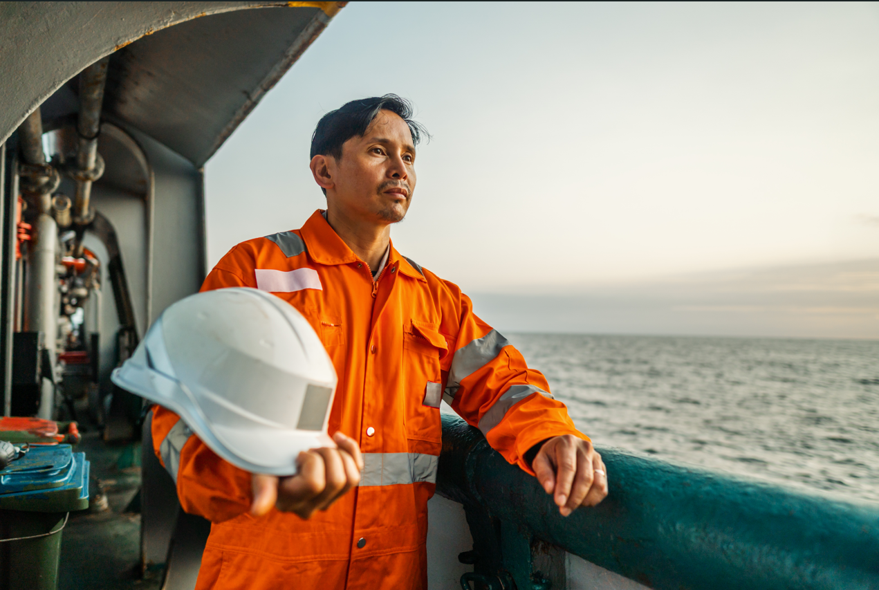 A contemplative seafarer overlooking the ocean at sunset, symbolizing the solitude and reflection experienced by maritime professionals.
