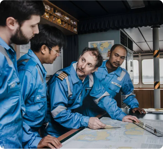 Diverse maritime crew collaborating over nautical charts in ship's control room, highlighting teamwork and strategic planning in maritime operations.