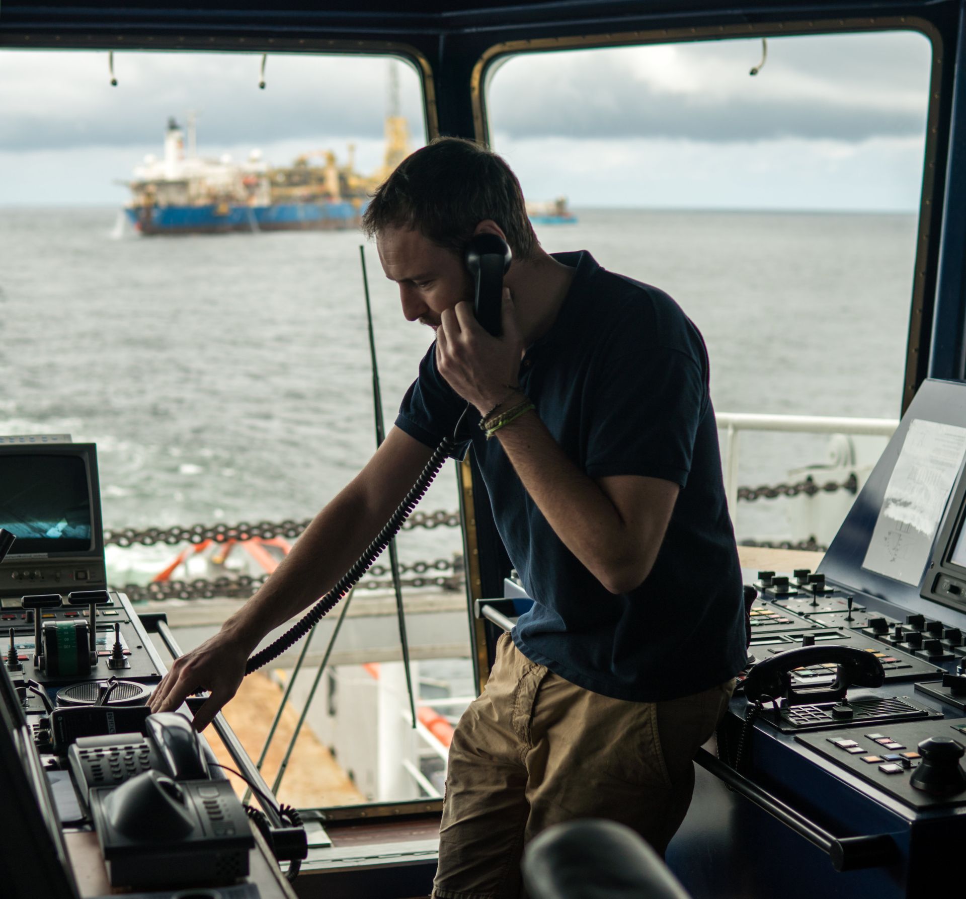 Maritime officer communicating via VHF radio in the bridge of a vessel, overseeing maritime operations and ensuring safe navigation.
