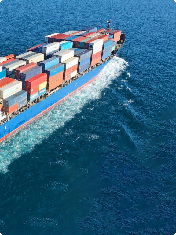 Aerial view of a large cargo ship with colorful containers sailing on blue water, showcasing the scale of maritime freight transport.