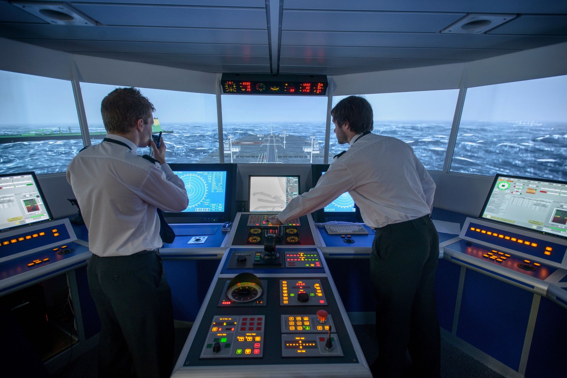 Ship officers monitoring navigational equipment and coordinating on the bridge in simulated adverse weather conditions.