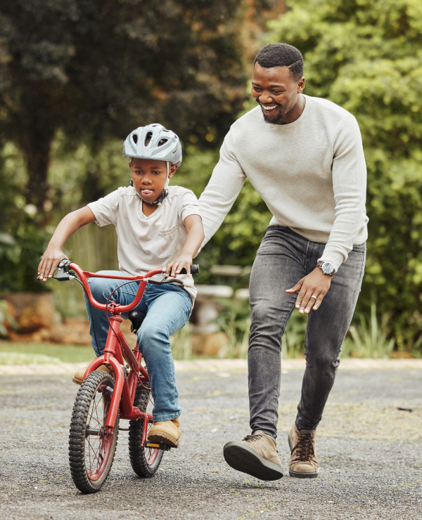 Dad guiding his son as he learns to ride a bicycle.