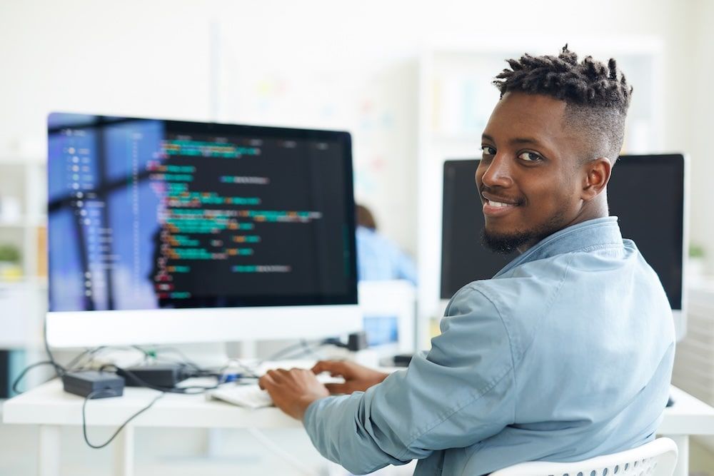 Man smiling while typing code on a computer screen