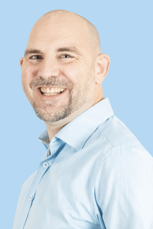 Side profile of a smiling man in a light blue shirt, exuding a friendly and approachable demeanor.