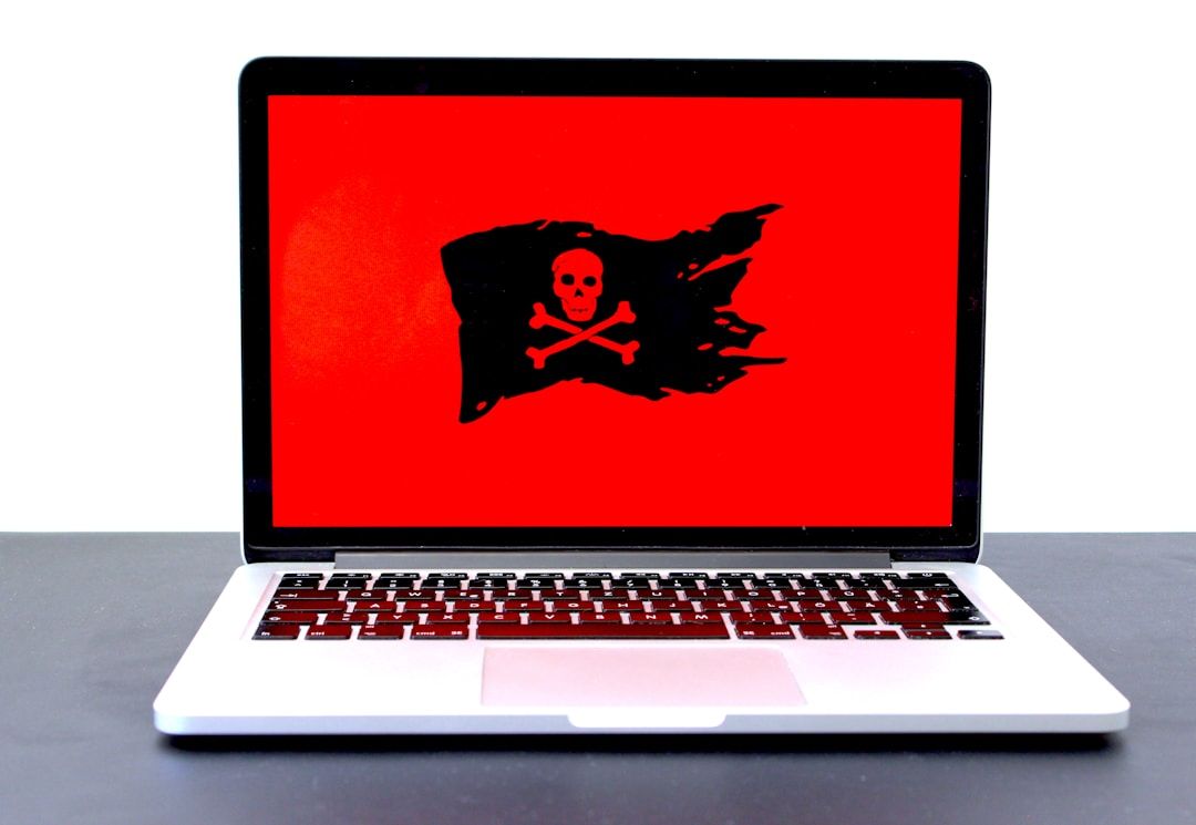 A laptop displaying a red screen with a black tattered flag and crossed-bones symbol, suggesting a malware or security warning.