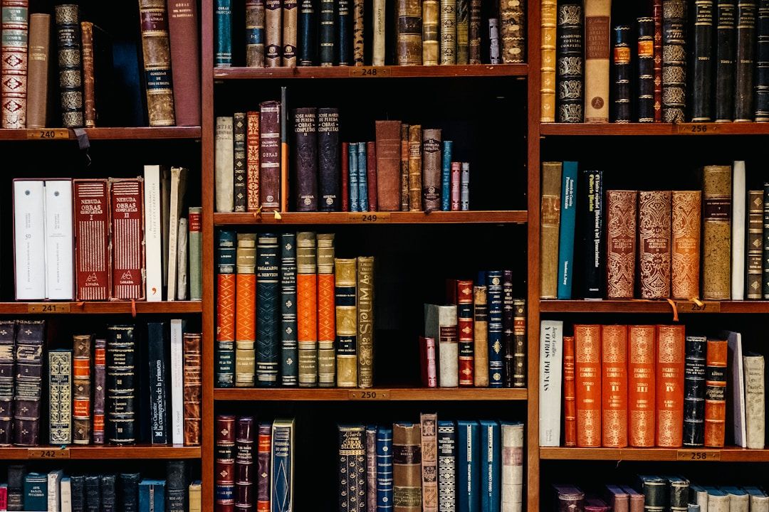 A wall of wooden bookshelves filled with rows of colorful vintage books in various sizes and bindings.