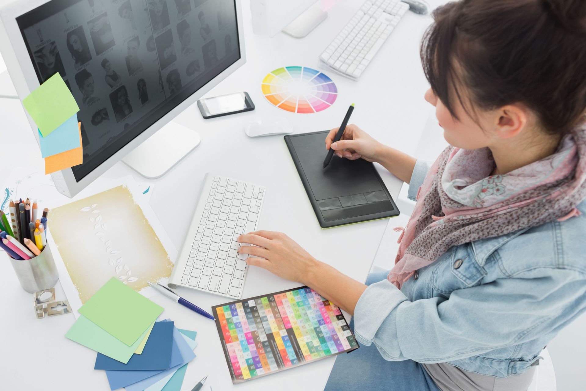 Person using a digital drawing tablet and desktop computer for graphic design and creative content creation.