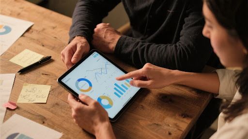 Ein Coach und ein Coachee arbeiten gemeinsam an einem Tablet an einer komplexen Projektaufgabe für die IPMA-Zertifizierung.