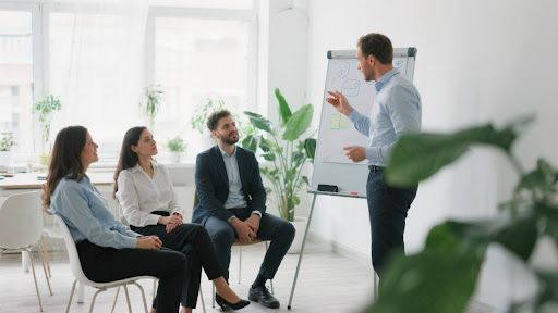 Ein Coach leitet ein interaktives Gruppen-Coaching mit einem diversen Team in einem modernen Besprechungsraum.
